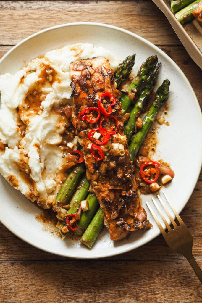 Filete de Salmón al Horno con Espárragos y Vinagreta de Miel y Limón servido en un plato con puré de patatas. También queda muy bien con arroz o con una ensalada para una cena más ligera. | Receta de Paula's Apron