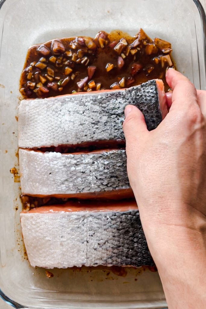 4 filetes de salmón con piel boca abajo encima de una bandeja de pyrex con vinagreta de miel, limón y miso para marinarlo. | Receta de Paula's Apron