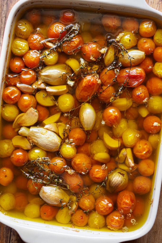 Fuente con tomates cherry confitados, su aceite, tomillo, chalotas y dientes de ajo.