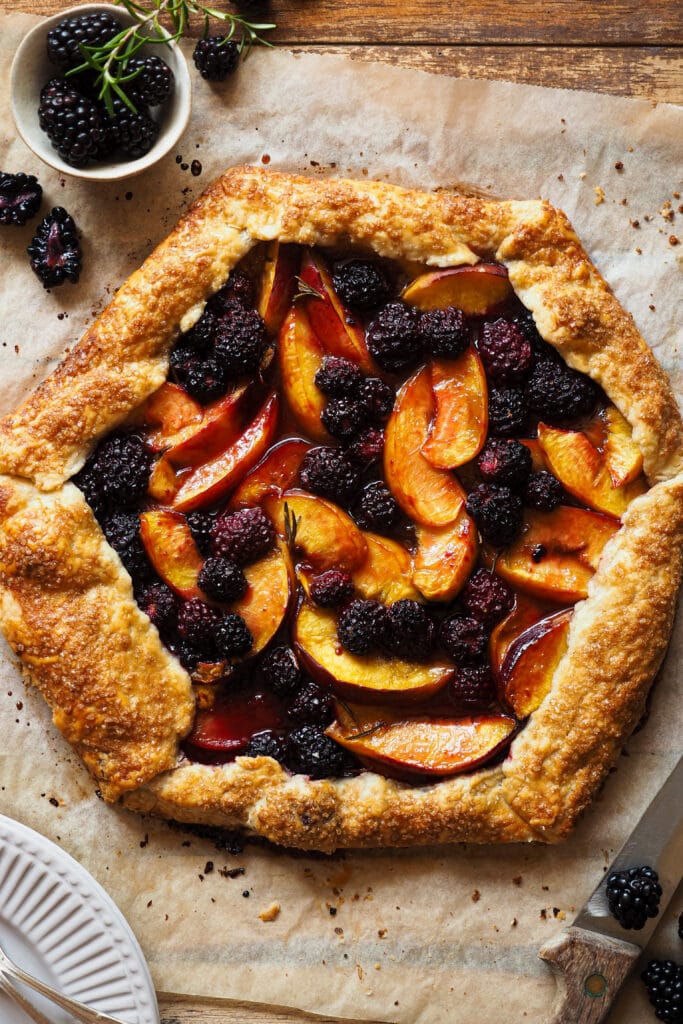 Esta Galette de Nectarina y Moras al Romero no es solo perfecta para disfrutar de la fruta que a finales de verano está en su mejor momento, sino que es la forma más fácil de que puedas disfrutar de una tarta totalmente casera sin complicarte. Es sencilla y rústica, nada de preocuparse de formas perfectas, pero está llena de sabor y texturas. Es un postre o merienda ideal para hacer cuando los días todavía son relativamente largos y queremos disfrutar al máximo de la fruta de temporada. | Receta de Paula's Apron