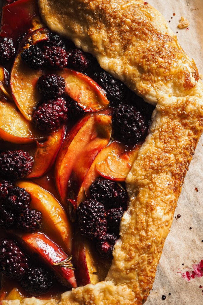 Esta Galette de Nectarina y Moras al Romero no es solo perfecta para disfrutar de la fruta que a finales de verano está en su mejor momento, sino que es la forma más fácil de que puedas disfrutar de una tarta totalmente casera sin complicarte. Es sencilla y rústica, nada de preocuparse de formas perfectas, pero está llena de sabor y texturas. Es un postre o merienda ideal para hacer cuando los días todavía son relativamente largos y queremos disfrutar al máximo de la fruta de temporada. | Receta de Paula's Apron