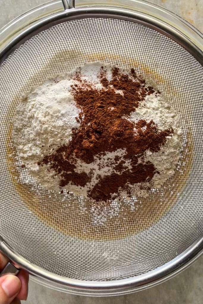 Tamiz con ingredientes secos (harina, canela, bicarbonato de sodio y levadura química) para banana bread o bizcocho de plátano.