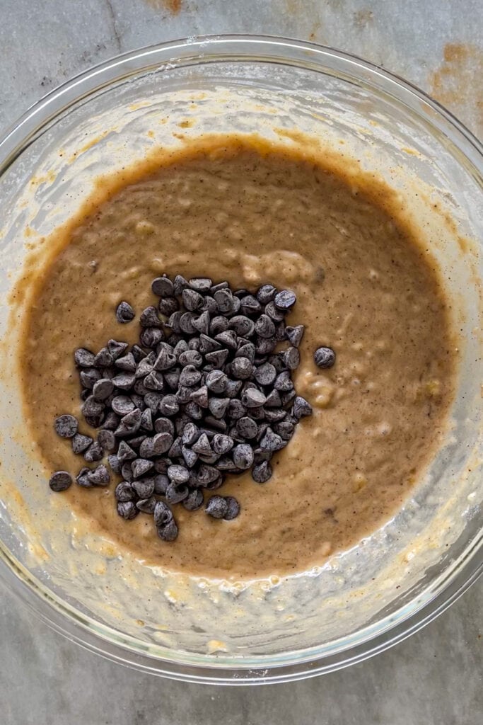 Masa para banana bread o bizcocho de plátano en un bol con chips de chocolate recién vertidas sin integrar.