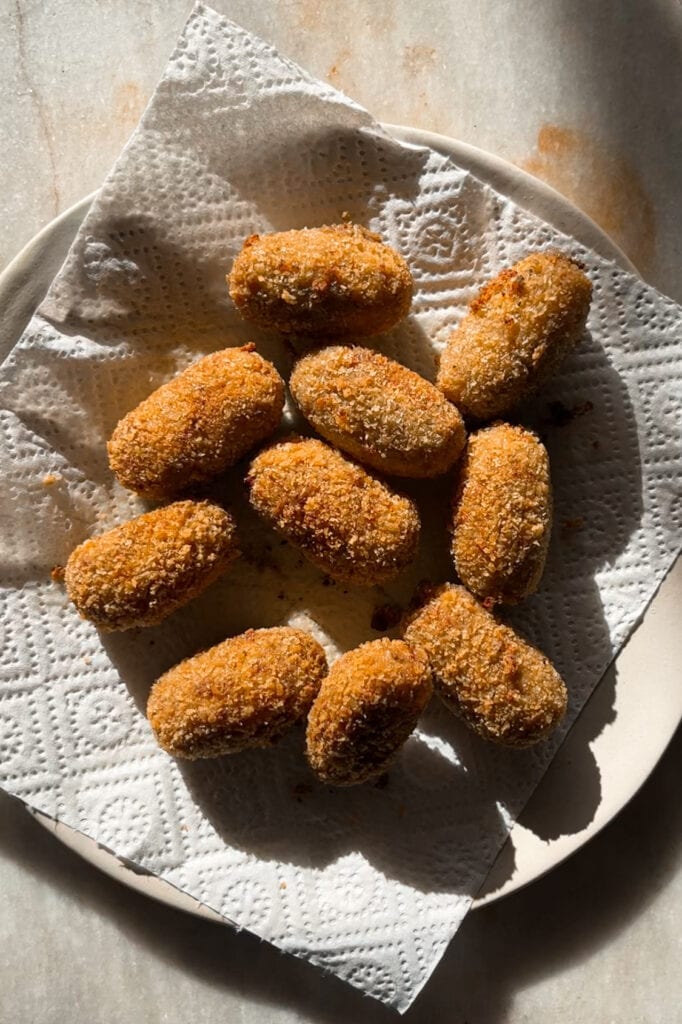 Croquetas de Setas cremosas por dentro y crujientes por fuera, con un increíble sabor umami gracias al boletus. Tamnbién llevan champiñones y te explico como hacer la bechamel perfecta para que no queden grumos. Estas croquetas son un homenaje al otoño e ideales para un buen picoteo o aperitivo. Aquí están escurriéndose ya fritas encima de papel de cocina. | Receta de Paula's Aspron