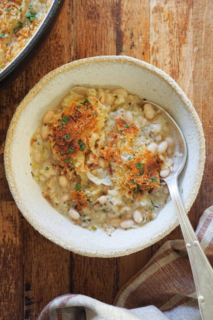 Esta receta de Gratén de Alubias y Puerro es una forma diferente y buenísima de disfrutar de esta legumbre. Es fácil de hacer y como resultado te quedan unas alubias suaves con una salsa extra cremosa que contrasta con el crujiente del gratinado. Otra cosa que me encanta es que se prepara en 15 minutos y el resto lo hace el horno, lo que encima te permite prepararlas con antelación y meterlas al horno cuando vayas a comer. En definitiva, un plato súper completo en todos los sentidos e ideal para entrar en calor estos meses fríos. | Receta de Paula's Apron