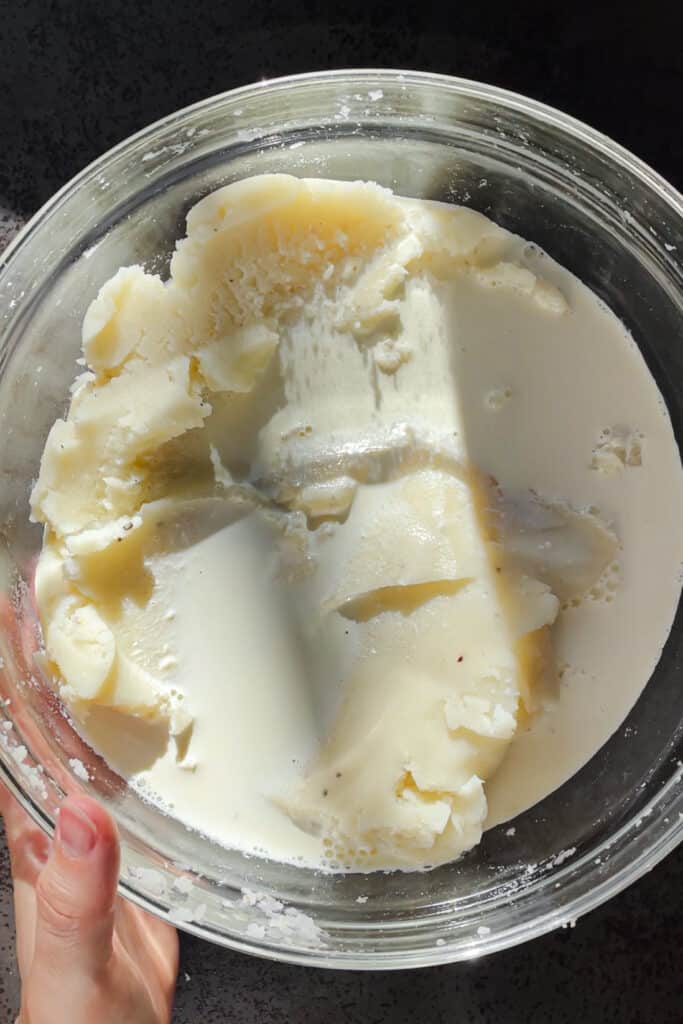 Nata infundida con ajo y romero vertida sobre puré de patatas antes de integrarla.