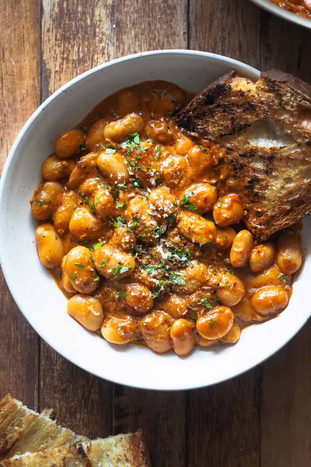 Alubias alla Vodka, un giro a la clásica Pasta alla Vodka usando legumbres que no deja indiferente. La salsa de tomate se potencia con el vodka, que además balancea muy bien el toque cremoso de esta salsa típica de pasta. Es una receta sencilla de preparar y en menos 25 minutos la tienes lista si usas alubias ya cocidas. Si quieres preparar algo reconfortante en gran cantidad, o si estás buscando una cena fácil entre semana que te llene y te haga sentir genial, no te puedo recomendar más estas alubias cremosas. | Receta de Paula's Apron