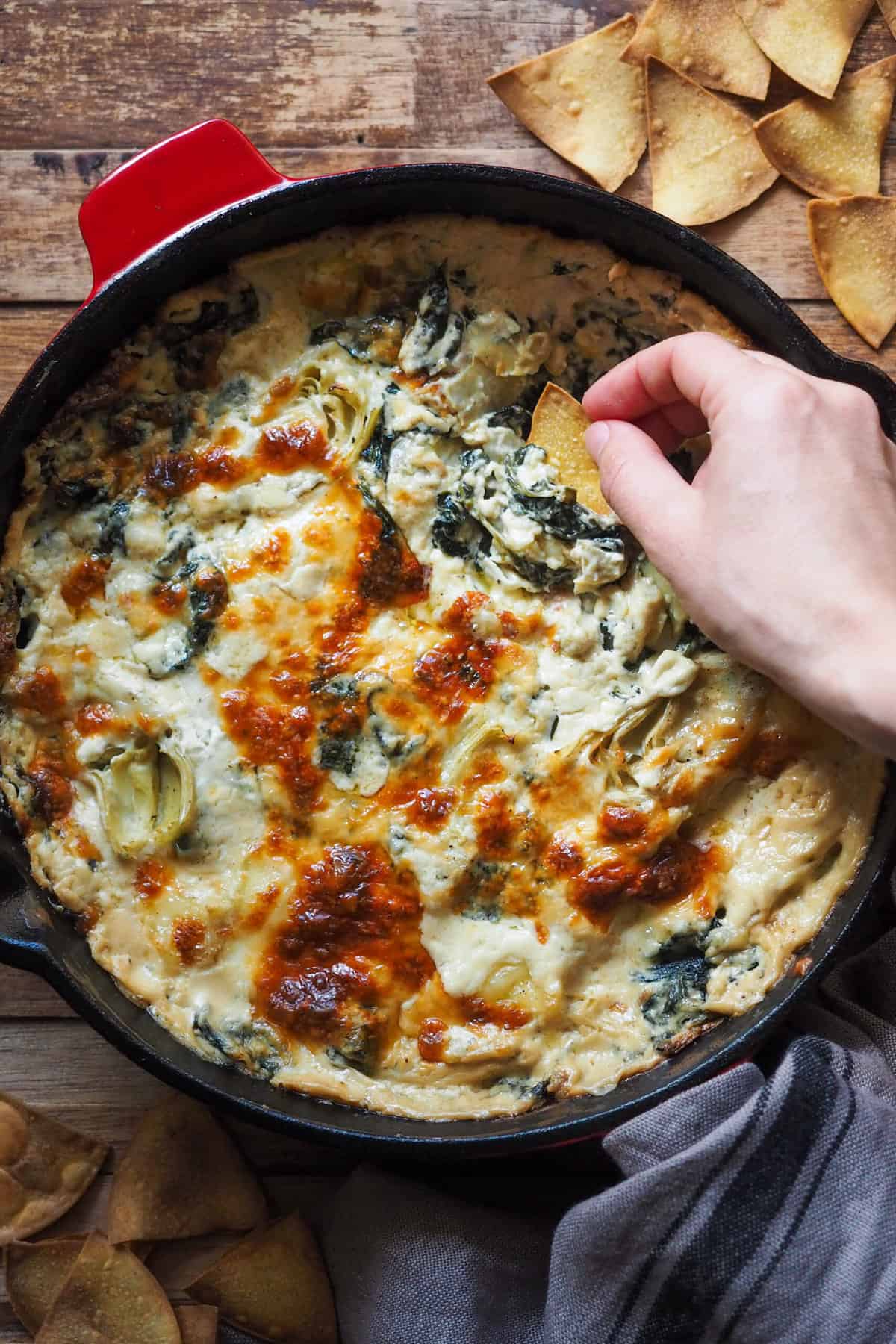 Este Dip de Espinacas y Alcachofas extra cremoso con totopos caseros combina producto de temporada, las espinacas y las alcachofas, con quesos deliciosos, aunque lo puedes hacer tranquilamente todo el año usando espinacas congeladas y alcachofas en conserva. Es un untable increíble como aperitivo o para picoteo que encima puedes preparar con antelación y meter en el horno cuando lo quieras servir. Para acompañar, unos totopos caseros al horno, aprovechando que lo encendemos para el dip, y, el resto, disfrute del bueno. | Receta de Paula's Apron