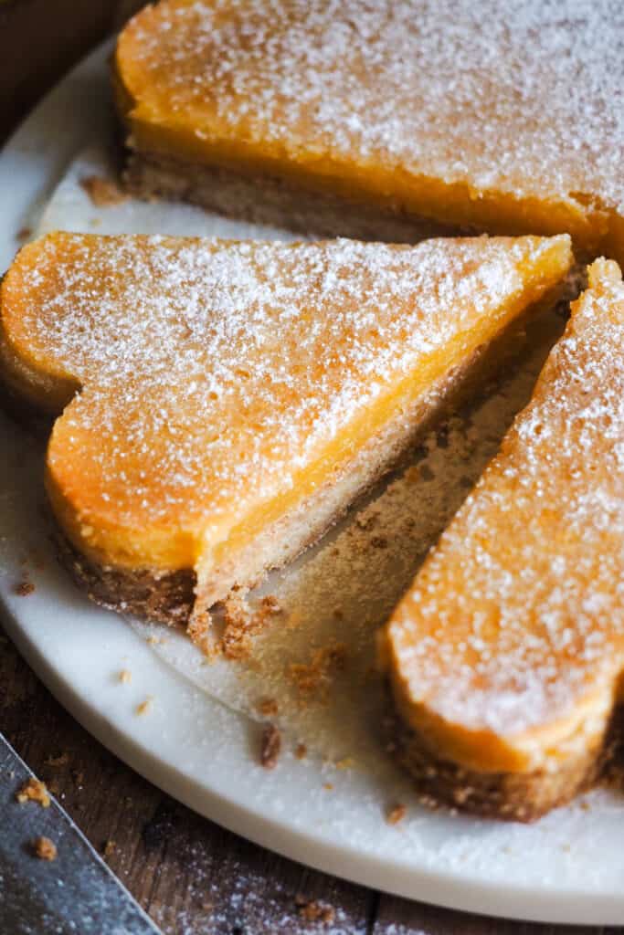 Las Lemon Bars son un postre muy popular en la repostería estadounidense, y no me extraña. Consisten en una base de masa crujiente y quebradiza, similar al shortbread, y están cubiertas con una capa de limón suave y ligeramente ácida. Son un dulce delicioso y perfecto para cualquier ocasión, ya sea una celebración, como postre o merienda. ¡Estas barritas de limón siempre sorprenden! | Receta de Paula's Apron