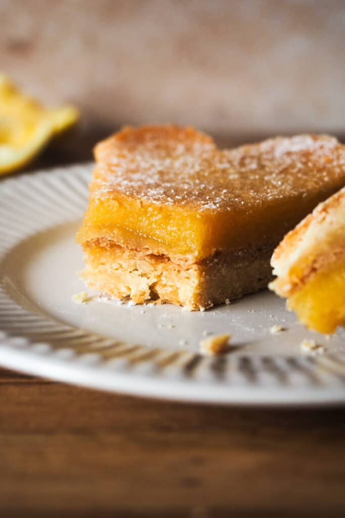 Las Lemon Bars son un postre muy popular en la repostería estadounidense, y no me extraña. Consisten en una base de masa crujiente y quebradiza, similar al shortbread, y están cubiertas con una capa de limón suave y ligeramente ácida. Son un dulce delicioso y perfecto para cualquier ocasión, ya sea una celebración, como postre o merienda. ¡Estas barritas de limón siempre sorprenden! | Receta de Paula's Apron