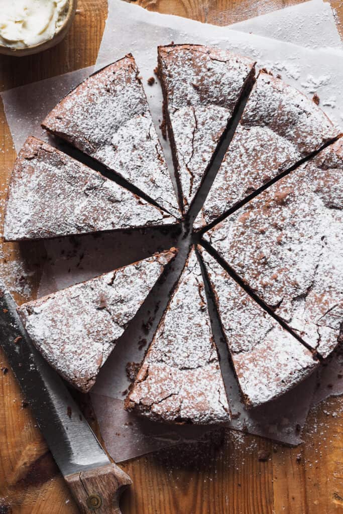 Torta Tenerina! Un clásico italiano, esta tarta de chocolate se caracteriza por su textura densa y húmeda en el interior parecida a un brownie y una superficie crujiente. Es perfecta para cualquier ocasión, sencilla de preparar con solo 5 ingredientes pero impresionante en su sabor y presentación. Un postre fácil increíble, ¡Anímate a probar este delicioso postre italiano! | Receta de Paula's Apron