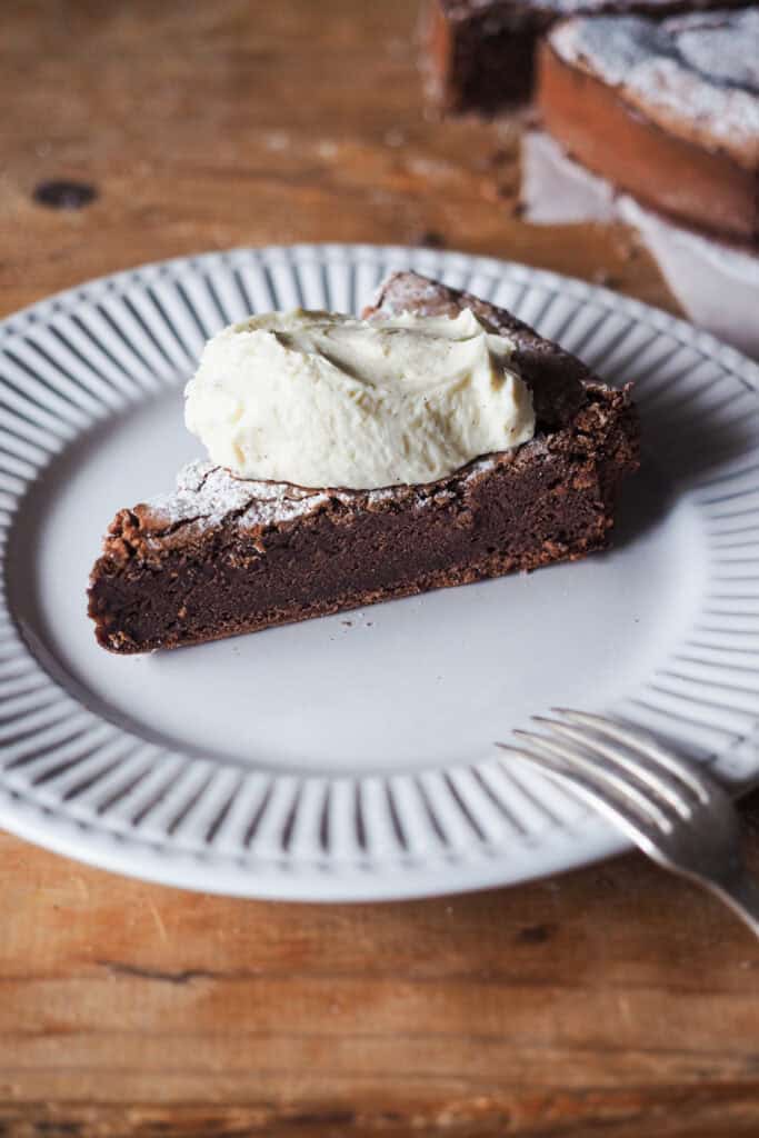 Torta Tenerina! Un clásico italiano, esta tarta de chocolate se caracteriza por su textura densa y húmeda en el interior parecida a un brownie y una superficie crujiente. Es perfecta para cualquier ocasión, sencilla de preparar con solo 5 ingredientes pero impresionante en su sabor y presentación. Acompañada de una suave crema de mascarpone, se convierte en el postre ideal para compartir con familia y amigos. ¡Anímate a probar este delicioso postre italiano! | Receta de Paula's Apron