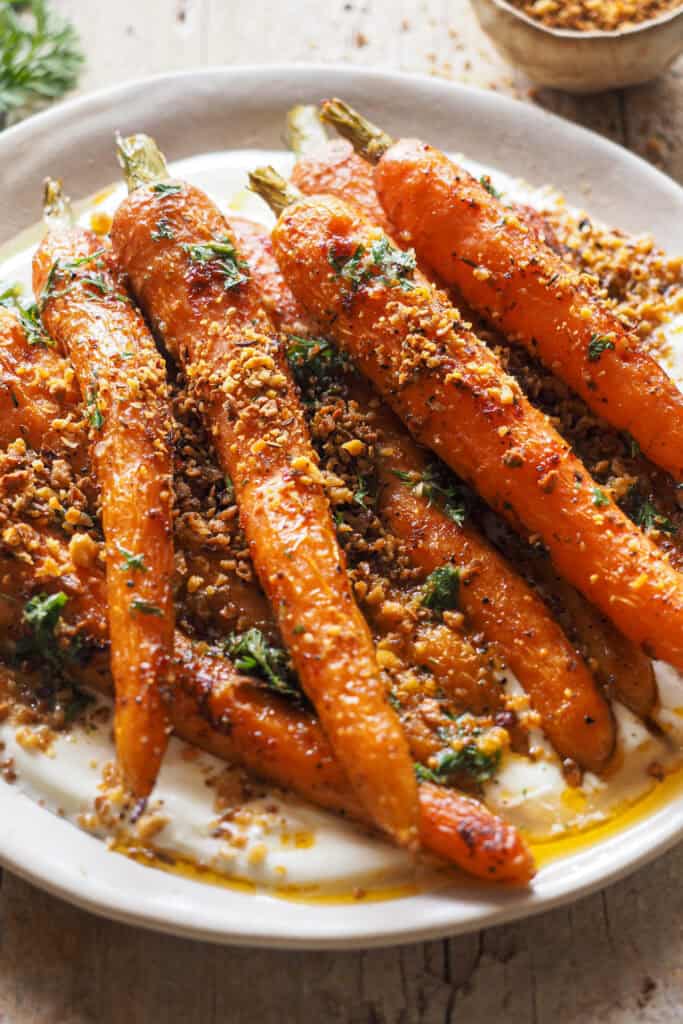 Zanahorias asadas con harissa, acompañadas de una refrescante salsa de yogur y crujientes migas de garbanzos con za'atar son perfectas como guarnición, como entrante o como plato principal ligero. Además la receta es un combo de sabores picantes, cremosos y crujientes que te van a enamorar. | Receta de Paula's Apron