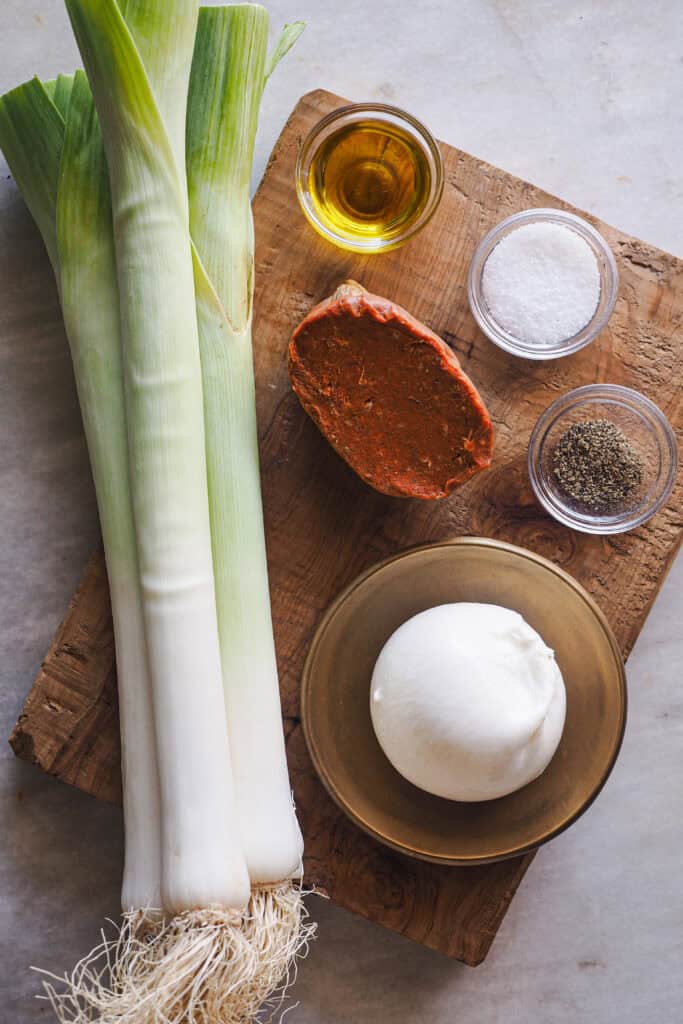 Ingredientes Puerros al Horno con Sobrasada y Burrata sobre tabla de madera
