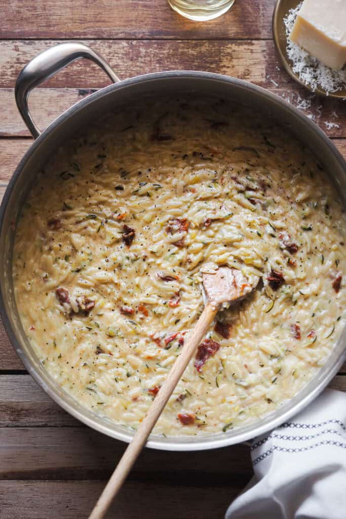 Menos laborioso que un risotto, pero igual de cremoso y sabroso, este Orzo Cremoso con Calabacín y Limón (Falso Risotto de Orzo con Calabacín y Limón u Orzotto de Calabacín y Limón) es comfort food veraniego del bueno. Lleno de sabores con el calabacín, limón y tomate seco y extra cremoso gracias a un toque de parmesano y mascarpone es de los mejores platos que se pueden hacer para cerrar el verano. | Receta de Paula's Apron