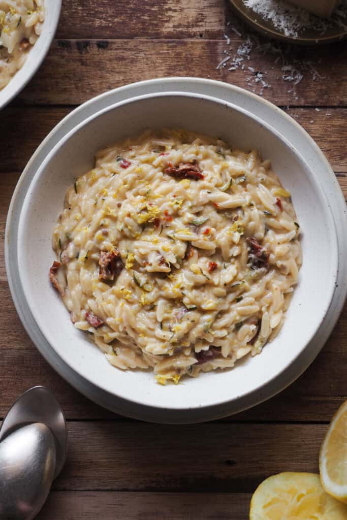 Menos laborioso que un risotto, pero igual de cremoso y sabroso, este Orzo Cremoso con Calabacín y Limón (Falso Risotto de Orzo con Calabacín y Limón u Orzotto de Calabacín y Limón) es comfort food veraniego del bueno. Lleno de sabores con el calabacín, limón y tomate seco y extra cremoso gracias a un toque de parmesano y mascarpone es de los mejores platos que se pueden hacer para cerrar el verano. | Receta de Paula's Apron