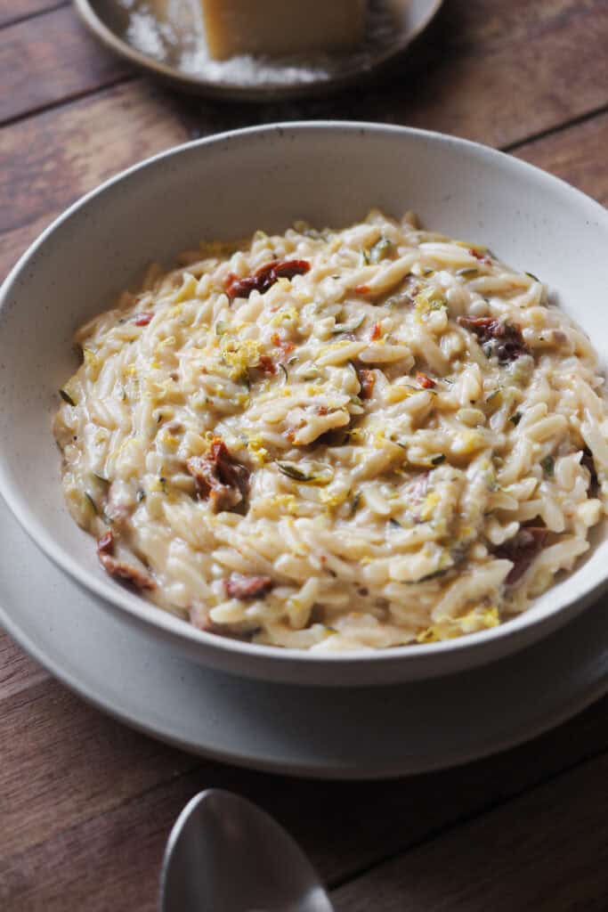 Menos laborioso que un risotto, pero igual de cremoso y sabroso, este Orzo Cremoso con Calabacín y Limón (Falso Risotto de Orzo con Calabacín y Limón u Orzotto de Calabacín y Limón) es comfort food veraniego del bueno. Lleno de sabores con el calabacín, limón y tomate seco y extra cremoso gracias a un toque de parmesano y mascarpone es de los mejores platos que se pueden hacer para cerrar el verano. | Receta de Paula's Apron