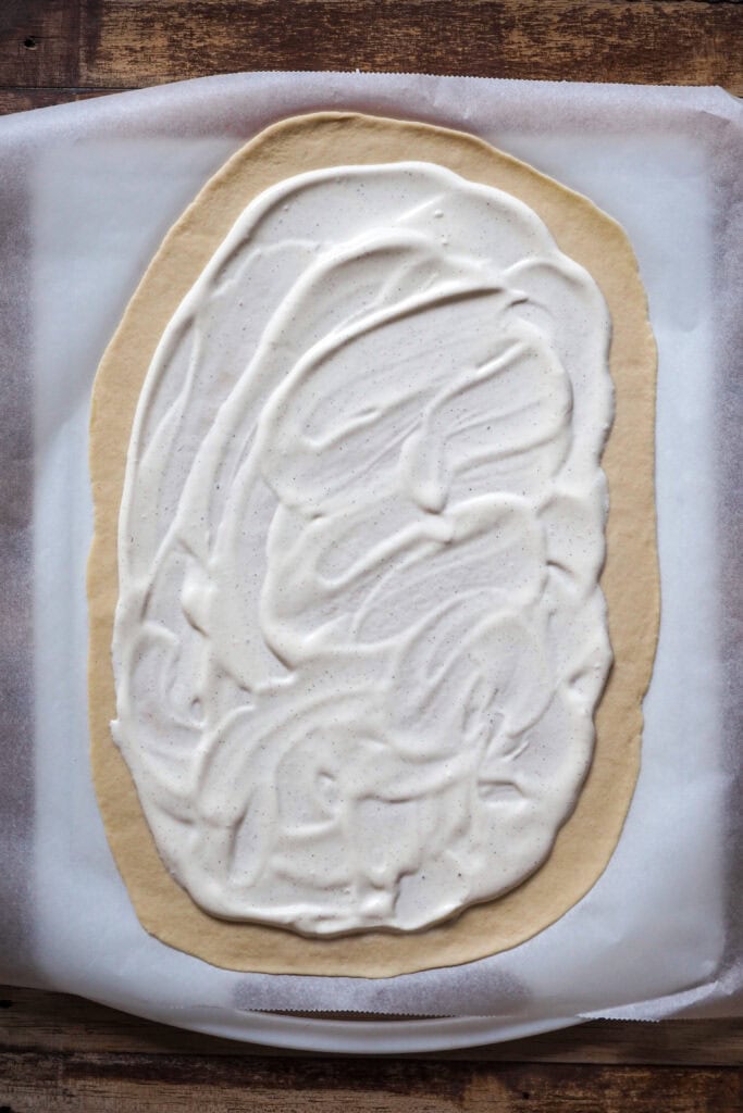 Paso 1 Flammkuchen: base de crème fraîche esparcida por encima de la masa finamente estirada.