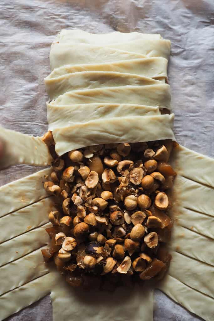 Paso 4 montar trenza de hojaldre rellena de manzana: trenzando el hojaldre superponiendo las tiras de hojaldre sobre el relleno.