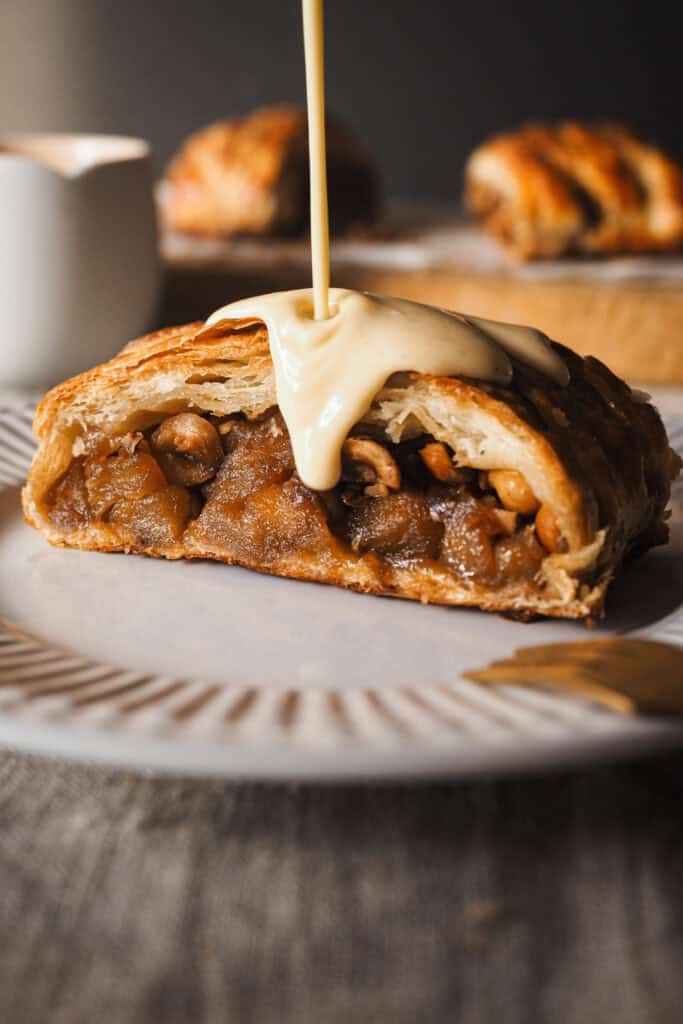 Hoy vamos con uno de esos postres fáciles y resultones que siempre te hacen quedar bien, una Trenza de Hojaldre Rellena de Manzana con Crema Inglesa. El hojaldre va relleno con manzana ligeramente pochada (para que no quede dura en el poco tiempo de horno que necesita la trenza) y avellanas para un toque crujiente dentro del mismo relleno. Lo podríamos dejar aquí, pero hoy como acompañamiento, para variar del típico helado, crema inglesa. Su aroma a vainilla y untuosidad no le pueden ir mejor ni al hojaldre ni a la manzana, y ya verás que es cero complicada. Es un postre que puedes preparar con antelación y todo junto hace un combo espectacular. | Receta de Paula's Apron