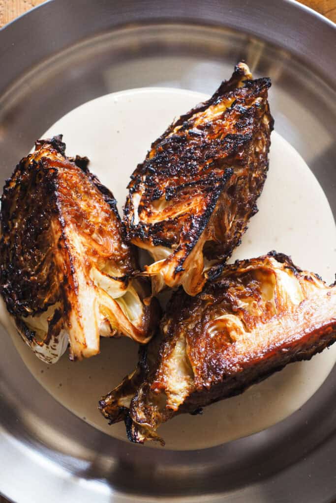 ¿Crees que no te gusta la col? Prepárate para cambiar de opinión con esta receta de Col al Horno con Miso y Crema de Anacardos, una nueva idea para transformar esta humilde verdura en un plato lleno de sabor. La col va asada con un toque umami de miso y acompañada de una base cremosa de anacardos que querrás usar con todo. Para rematar, un aliño ligeramente ácido que lo redondea todo, semillas de sésamo y cebollino. Es una receta fácil, saludable y simplemente deliciosa apta para veganos, celíacos e intolerantes a la lactosa. | Receta de Paula's Apron