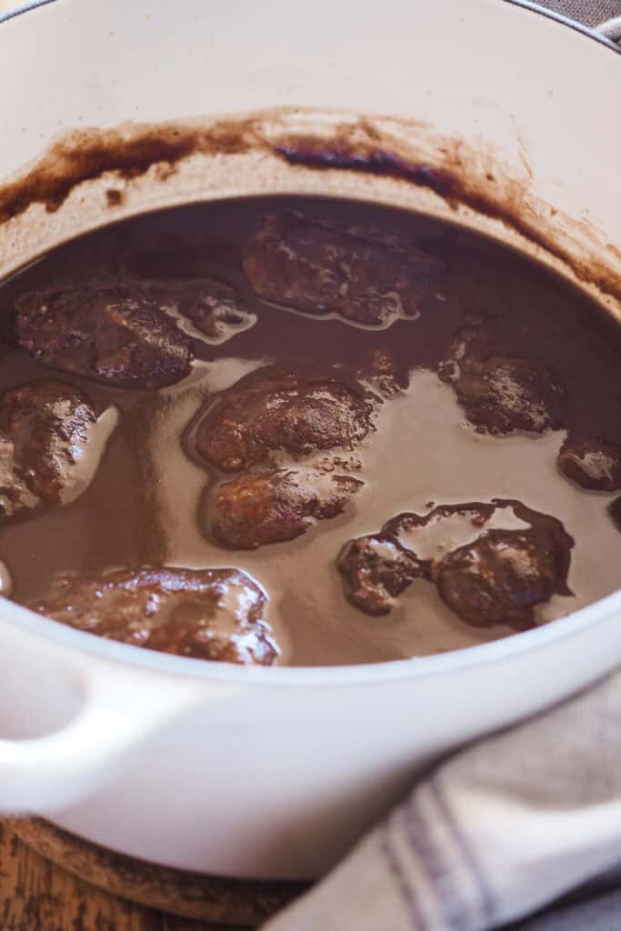 Mis recetas favoritas son sin duda las recetas tradicionales como esta, unas Carrilleras al Vino Tinto que te quitan el sentido y que harían orgullosa a mi abuela. Quedan melosas, tiernas y la salsa es de esas para mojar todo el pan del mundo, porque no querrás dejar ni una gota. Como buen guiso, requiere cariño y paciencia, pero con 4 pasos lo tienes, no pide más. Acompáñalas de puré de chirivía para una opción ligera, de polenta cremosa o el clásico puré de patatas y a desmayarte de placer cuando les pegues un bocado. | Receta de Paula's Apron