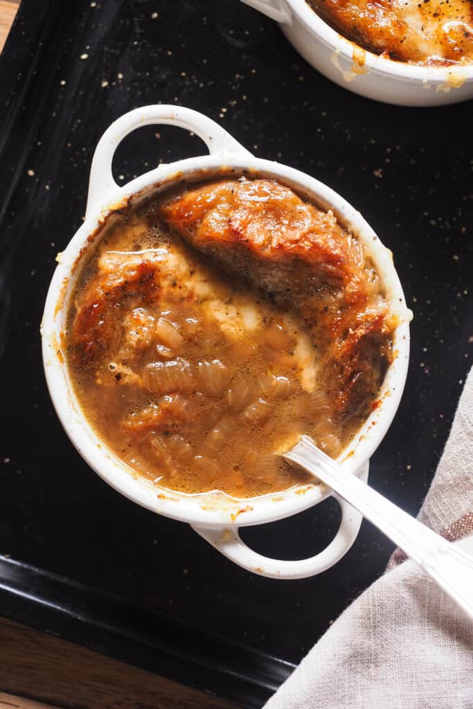 Mi receta favorita de sopa de cebolla francesa de todos los tiempos: sorprendentemente fácil de hacer y llena de sabor. Es un plato clásico de la cocina francesa y muy reconfortante, lo que lo hace ideal para cuando hace frío o para fiestas navideñas. ¿La clave? Un buen caldo y tiempo para caramelizar bien la cebolla. Tradicionalmente, y como vamos a ver hoy, se sirve con pan y queso, para mi lo que lleva una sopa de cebolla al siguiente nivel. ¡Espero que te guste tanto como a mi! | Receta de Paula's Apron