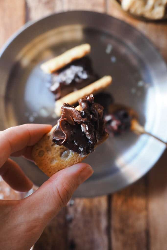 ¿Puede que sea el postre de chocolate más fácil del mundo? Puede, pero esta versión del clásico pan con chocolate, aceite y sal nunca deja a nadie indiferente. El chocolate queda suave, nada pesado, y le he dado un toque de naranja aprovechando que está de temporada pero puedes aromatizarlo como quieras o dejarlo tal cual (luego te dejo opciones). Para rematar, toque salado con sal marina en escamas, un buen aceite de oliva virgen extra y en lugar de unas tostadas típicas a mi me gusta acompañarlo con pan de pipas, que siempre siempre siempre sorprende. | Receta de Paula's Apron