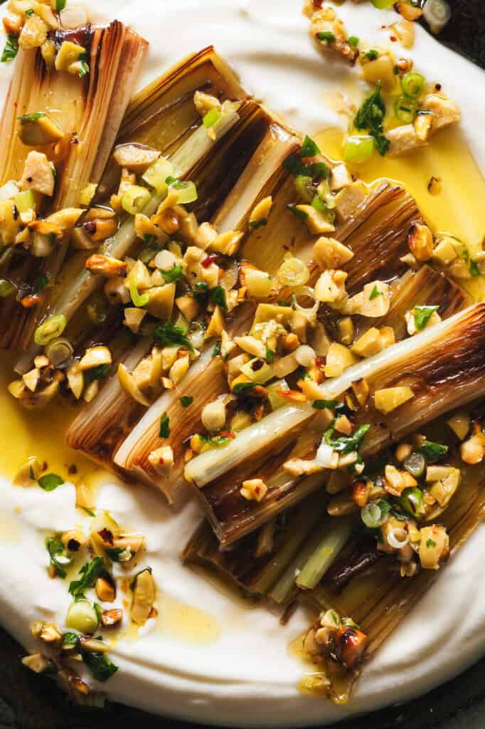 Nueva idea para demostrarte que el puerro puede ser un protagonista increíble: Puerros Caramelizados con Aliño de Aceitunas y Pistachos. Hoy vamos a aprender una técnica alternativa a asarlos para también conseguir un puerro suave, dulzón y con una textura que se deshace en boca. Sólo necesitas 15 minutos más o menos y vamos a aprovechar el rato de cocción para preparar un topping y una base que van a llevar esta receta de un acompañamiento delicioso a un entrante espectacular. | Receta de Paula's Apron