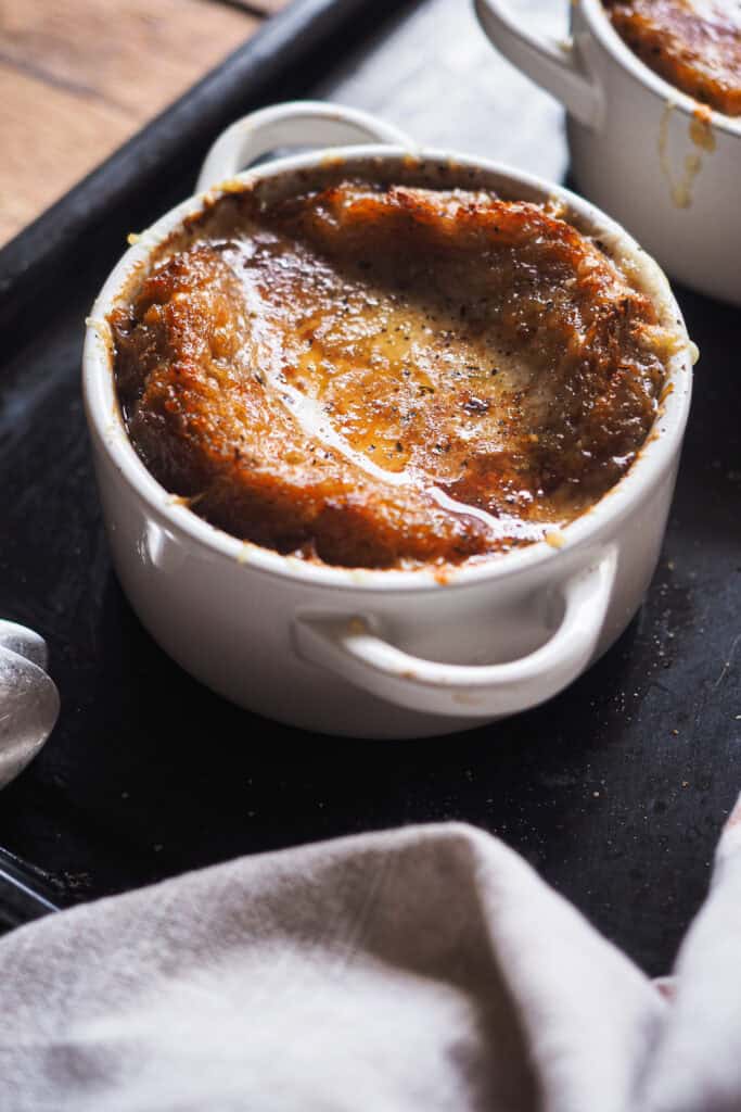 Mi receta favorita de sopa de cebolla francesa de todos los tiempos: sorprendentemente fácil de hacer y llena de sabor. Es un plato clásico de la cocina francesa y muy reconfortante, lo que lo hace ideal para cuando hace frío o para fiestas navideñas. ¿La clave? Un buen caldo y tiempo para caramelizar bien la cebolla. Tradicionalmente, y como vamos a ver hoy, se sirve con pan y queso, para mi lo que lleva una sopa de cebolla al siguiente nivel. ¡Espero que te guste tanto como a mi! | Receta de Paula's Apron
