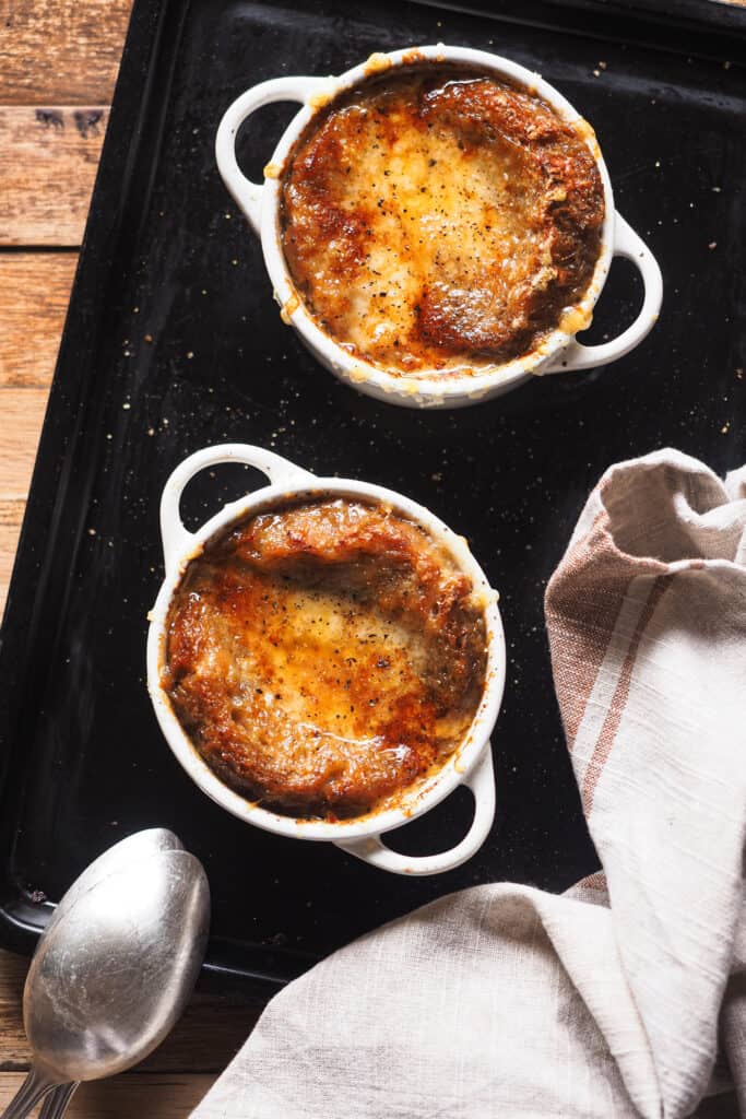 Mi receta favorita de sopa de cebolla francesa de todos los tiempos: sorprendentemente fácil de hacer y llena de sabor. Es un plato clásico de la cocina francesa y muy reconfortante, lo que lo hace ideal para cuando hace frío o para fiestas navideñas. ¿La clave? Un buen caldo y tiempo para caramelizar bien la cebolla. Tradicionalmente, y como vamos a ver hoy, se sirve con pan y queso, para mi lo que lleva una sopa de cebolla al siguiente nivel. ¡Espero que te guste tanto como a mi! | Receta de Paula's Apron