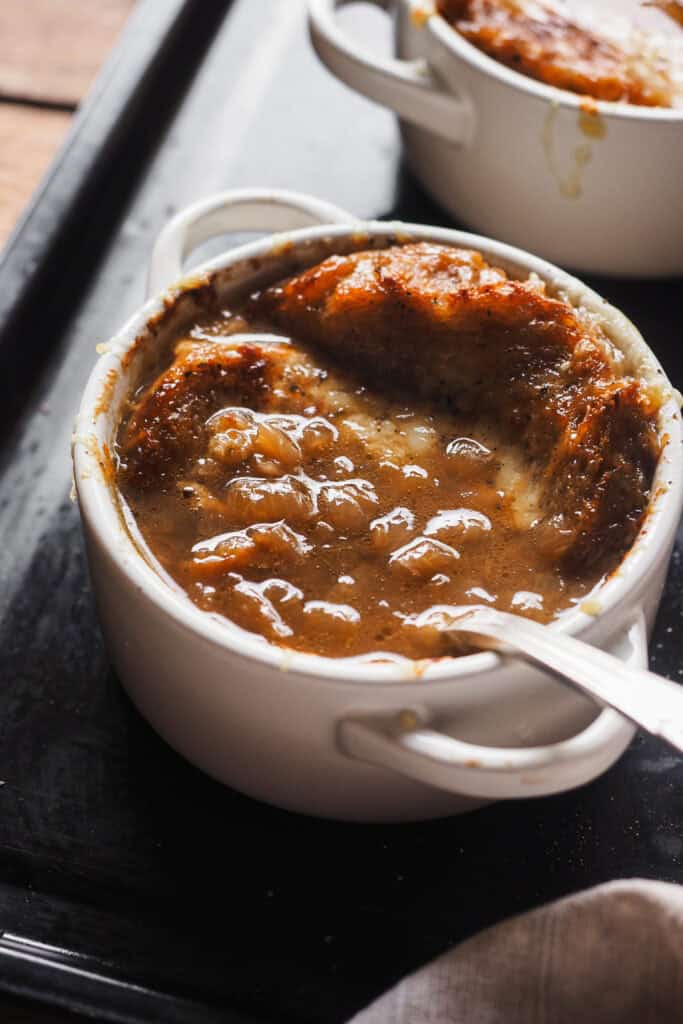 Mi receta favorita de sopa de cebolla francesa de todos los tiempos: sorprendentemente fácil de hacer y llena de sabor. Es un plato clásico de la cocina francesa y muy reconfortante, lo que lo hace ideal para cuando hace frío o para fiestas navideñas. ¿La clave? Un buen caldo y tiempo para caramelizar bien la cebolla. Tradicionalmente, y como vamos a ver hoy, se sirve con pan y queso, para mi lo que lleva una sopa de cebolla al siguiente nivel. ¡Espero que te guste tanto como a mi! | Receta de Paula's Apron