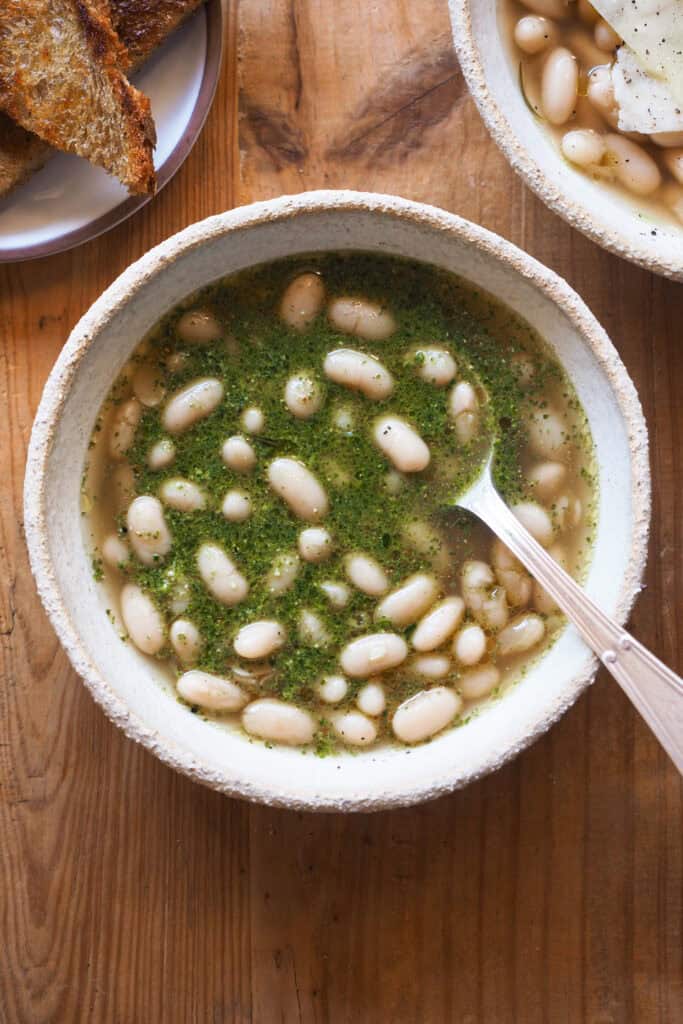 Estas alubias caldosas con pesto son un plato reconfortante y a la vez fresco, con mucho sabor por el caldo resultante de cocer alubias y el pesto. | Receta de Paula's Apron
