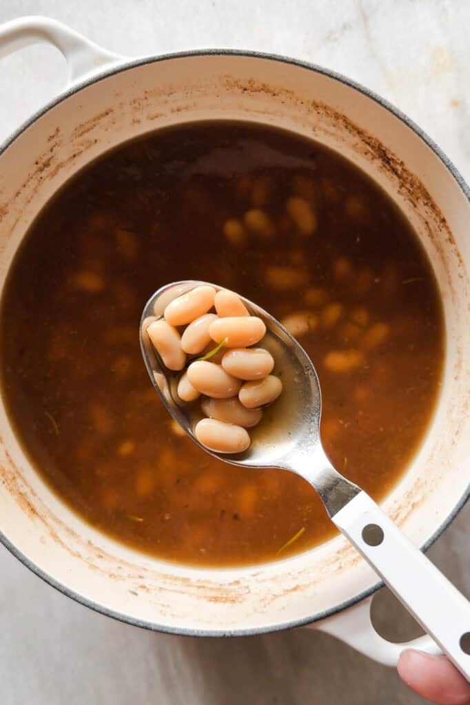 Cómo cocer alubias es algo que todos deberíamos saber hacer. Además de rebote te sale un caldo sabroso, nutritivo, fácil y versátil que puedes usar de mil formas, así como las alubias cocidas resultantes. Las alubias secas son mucho más económicas que comprarlas en bote, puedes hacer en cantidad y conservarlas para usarlas en una infinidad de platos de la misma forma que usarías las que vienen en conserva. Hoy vamos a ver además 2 opciones de sopas facilísimas y como pocharlas con verdura. | Receta de Paula's Apron