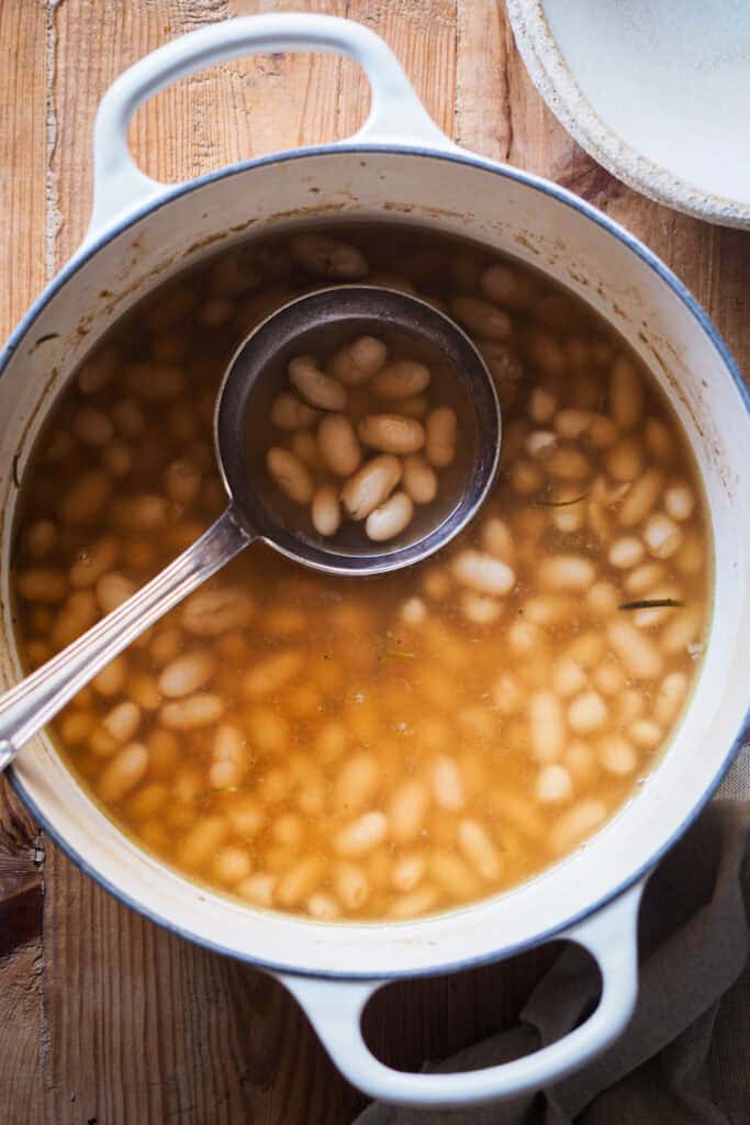 Cómo cocer alubias es algo que todos deberíamos saber hacer. Además de rebote te sale un caldo sabroso, nutritivo, fácil y versátil que puedes usar de mil formas, así como las alubias cocidas resultantes. Las alubias secas son mucho más económicas que comprarlas en bote, puedes hacer en cantidad y conservarlas para usarlas en una infinidad de platos de la misma forma que usarías las que vienen en conserva. Hoy vamos a ver además 2 opciones de sopas facilísimas y como pocharlas con verdura. | Receta de Paula's Apron