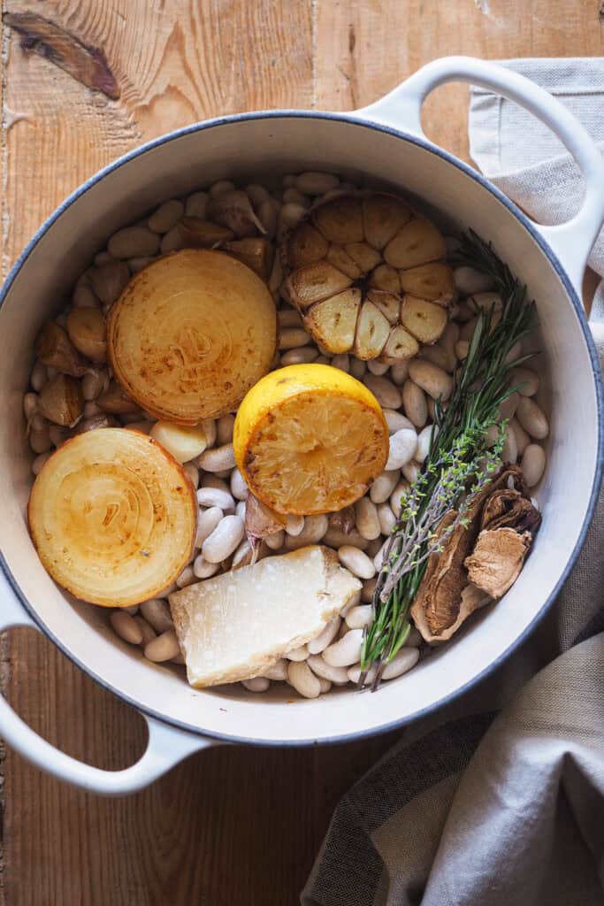 Olla con ingredientes para cocer alubias antes de cubrirlos con agua.