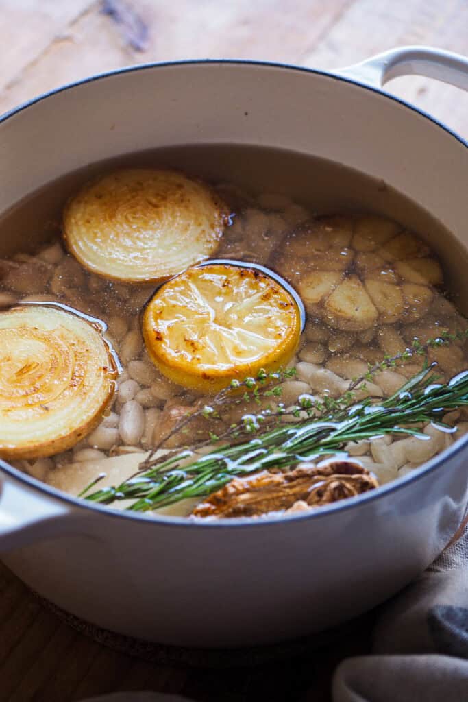 Cómo cocer alubias es algo que todos deberíamos saber hacer. Además de rebote te sale un caldo sabroso, nutritivo, fácil y versátil que puedes usar de mil formas, así como las alubias cocidas resultantes. Las alubias secas son mucho más económicas que comprarlas en bote, puedes hacer en cantidad y conservarlas para usarlas en una infinidad de platos de la misma forma que usarías las que vienen en conserva. Hoy vamos a ver además 2 opciones de sopas facilísimas y como pocharlas con verdura. | Receta de Paula's Apron