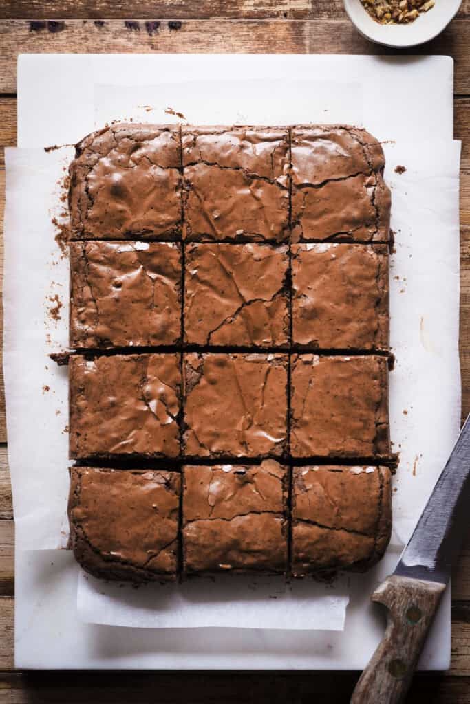 ¿En busca del brownie de chocolate perfecto? Después de semanas desarrollando esta receta, al fin te traigo la que para mi es la receta de brownie casero ideal. Tierno, pero sin ser abizcochado, húmedo y jugoso, pero ligero y suave a la vez, cero mazacote y con el punto de chocolate equilibrado para que no sea empalagoso. ¡Ah! Y con esa superficie brillante y quebradiza, ligeramente crujiente, que contrasta con la textura del interior, una mezcla perfecta entre "chewy" y "fudgy". Como toque final, y opcional, la cantidad justa de nueces para encontrarte un trocito aquí y allí pero sin que manden. ¡Ha sido la versión favorita entre todos mis amigos y familia, así que espero que te encante! | Receta de Paula's Apron