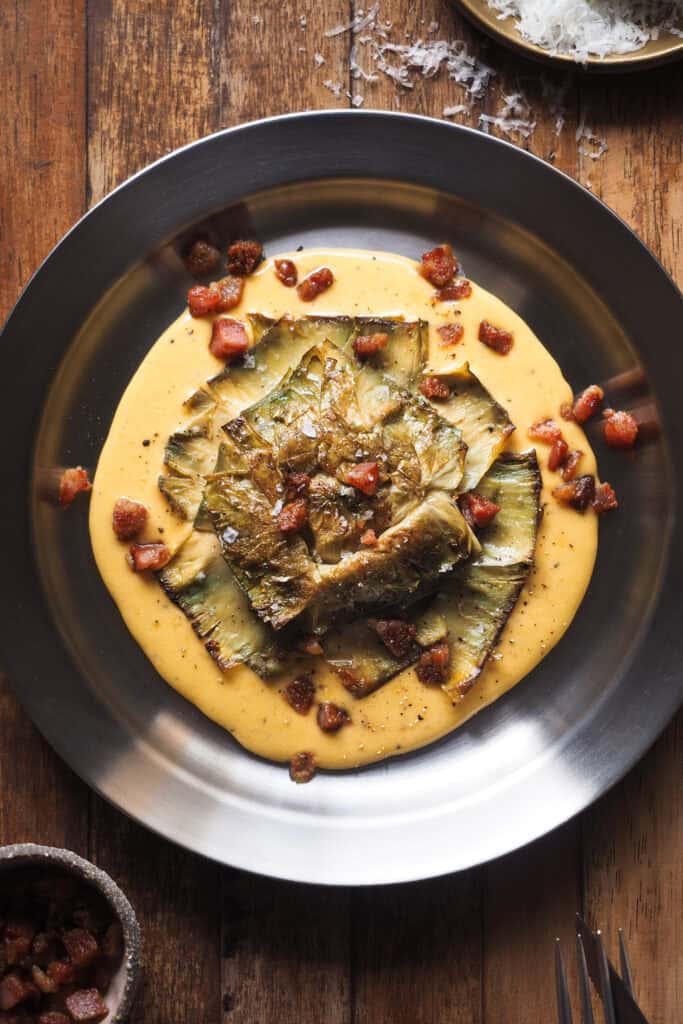 Si quieres impresionar en tu próxima comida o cena, esta Flor de Alcachofa a la Carbonara es lo que buscas. Nacida de unir dos de mis cosas favoritas en el mundo, la alcachofa y una salsa típica romana que no puede quedar relegada sólo a la pasta, el resultado es un plato sabroso, vistoso ¡y que parece de restaurante! | Receta de Paula's Apron