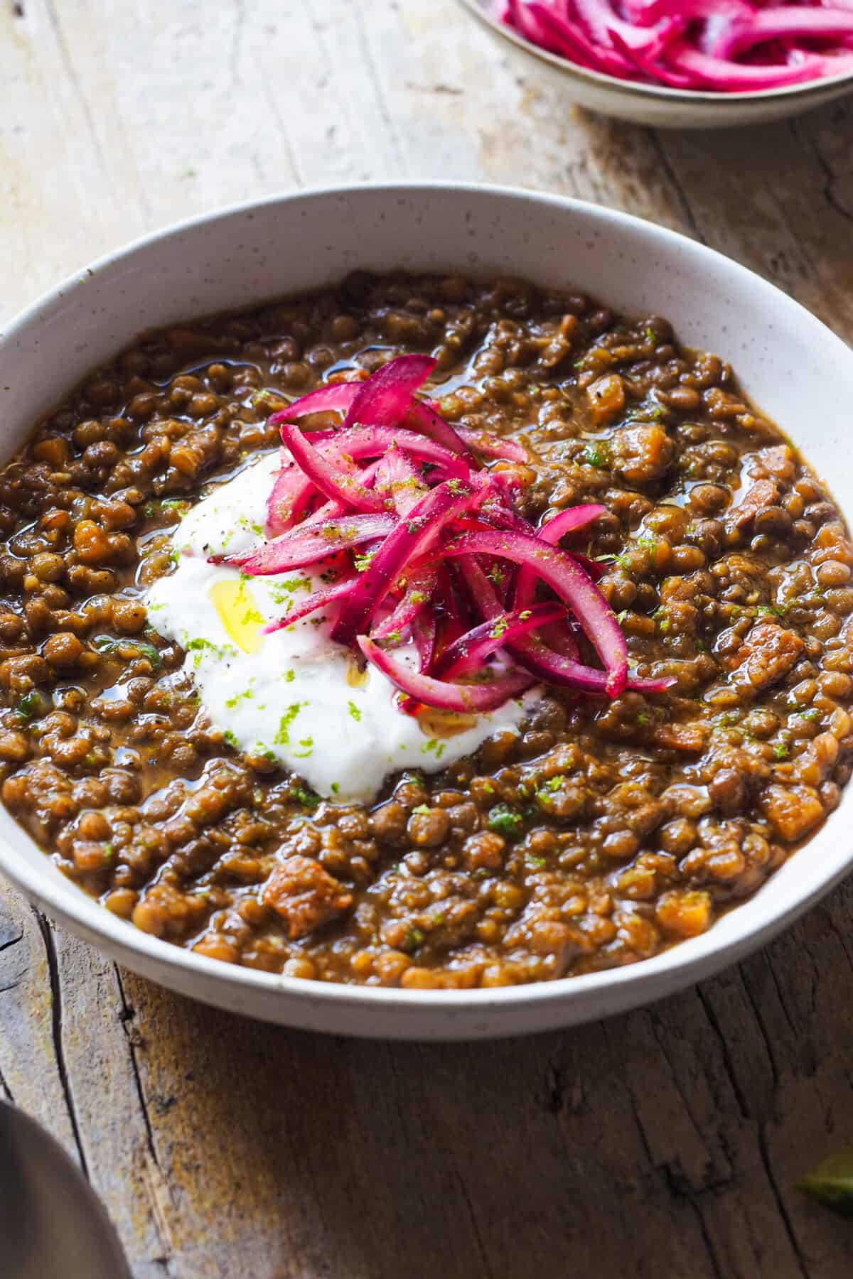 Aprende cómo hacer Lentejas con Chorizo especiadas y adáptalas como más te gusten. La versión de hoy es un plato de cuchareo riquísimo y los sabores son una fusión entre León, Marruecos y mi toque personal jeje. Me encanta darle un toque final ácido al plato, que al ser algo contundente y graso le queda súper bien para refrescar. Y como no soy de piparras, pues un encurtido rápido de cebolla que encima aporta mucho color, junto con yogur y lima para equilibrar las especias. Son muy versátiles por lo que juega con los ingredientes como quieras, ya verás que es tan fácil como hacer un buen sofrito, añadir las lentejas y guisar. | Receta de Paula's Apron