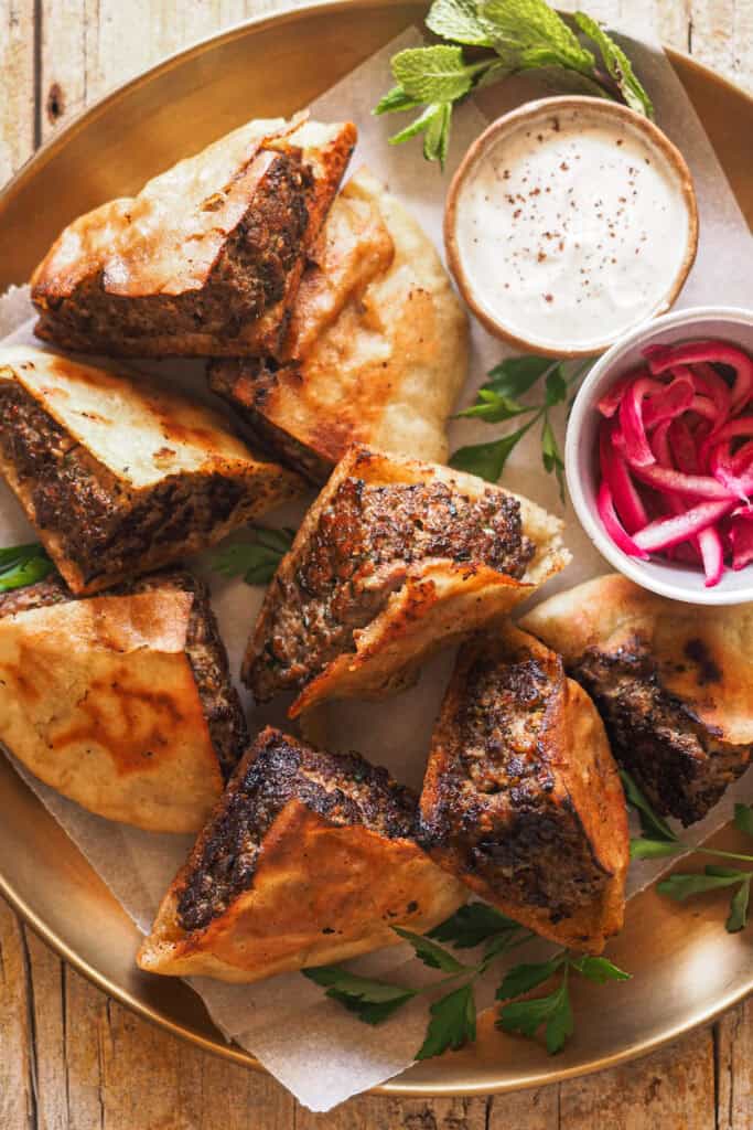 Este ha sido el último hit en casa, ¡los Arayes! Pita rellena de carne especiada y marcada a la plancha o asada en una barbacoa o al horno hasta que el relleno queda jugoso y al punto y el pan crujiente. Los puedes disfrutar como plato principal en una comida o cena o bien como aperitivo para compartir. Los comas cuando los comas, lo que es obligatorio es acompañarlos con la salsa de yogur y tahini que te voy a compartir. | Receta de Paula's Apron