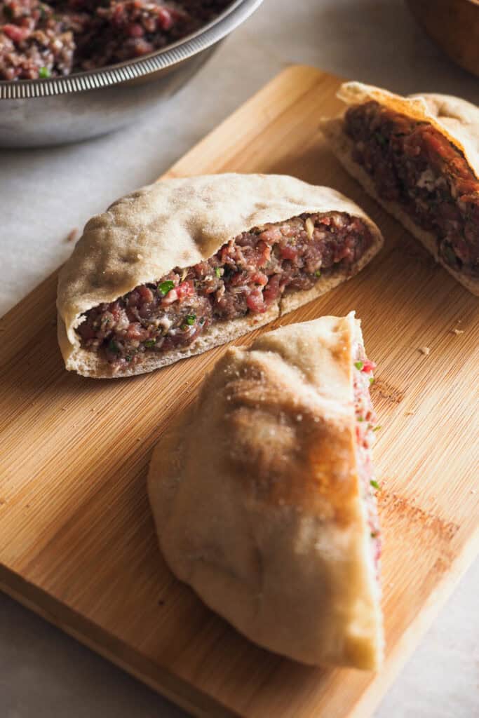Pan pita partido por la mitad relleno de carne especiada para hacer arayes.