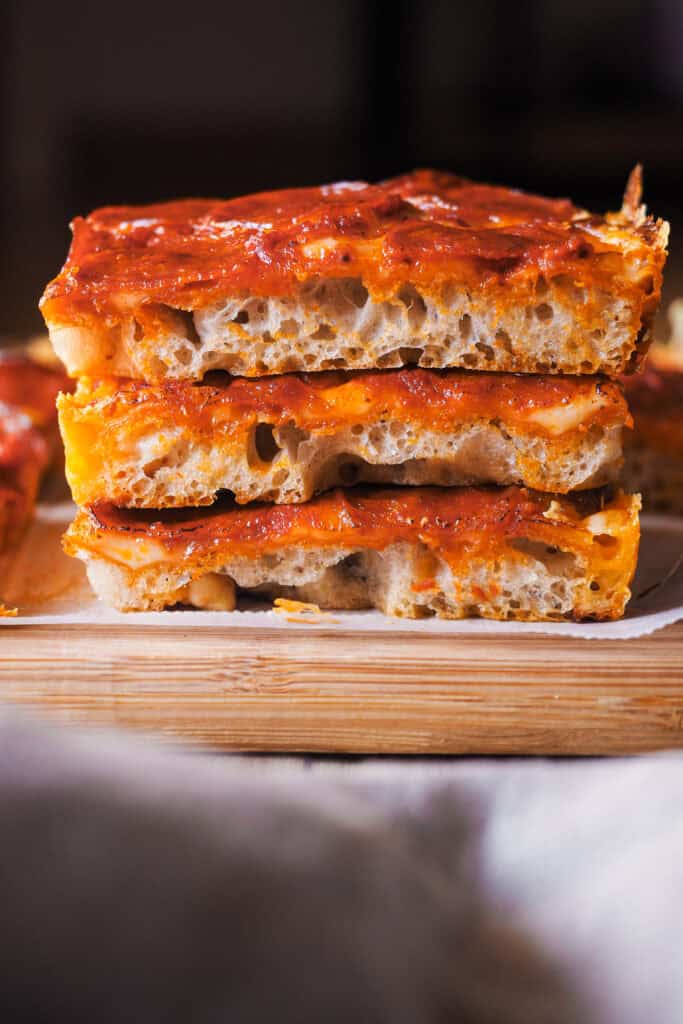 Estoy de vuelta una vez más con pizzas por el mundo, porque existen un montón de tipos de pizza increíbles como la Pizza Estilo Detroit que te traigo hoy y encima con una masa que no necesita amasado. Imagínate una base suave, ligera y esponjosa, parecida a la de la focaccia, una costra de queso por todo el perímetro y el topping que más te guste, ¿suena bien no? Hoy en concreto voy a usar el topping típico de la "Detroit-Style Pizza" con queso, salsa de tomate y pepperoni. ¡Ah! Y no te extrañes por el orden en que los pongo, es algo que caracteriza a este tipo de pizza. | Receta de Paula's Apron