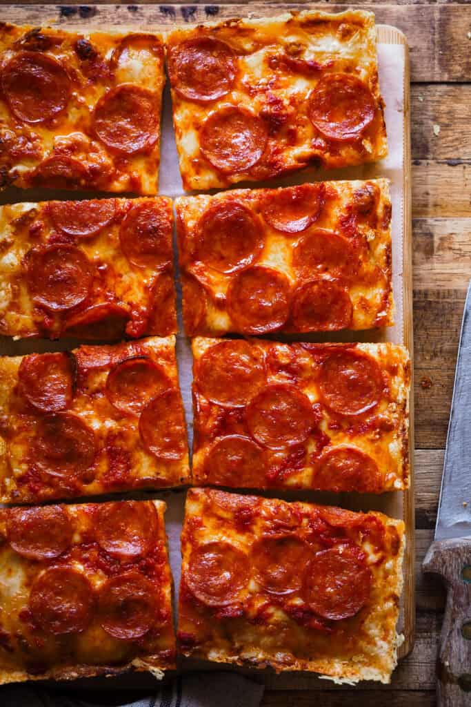 Estoy de vuelta una vez más con pizzas por el mundo, porque existen un montón de tipos de pizza increíbles como la Pizza Estilo Detroit que te traigo hoy y encima con una masa que no necesita amasado. Imagínate una base suave, ligera y esponjosa, parecida a la de la focaccia, una costra de queso por todo el perímetro y el topping que más te guste, ¿suena bien no? Hoy en concreto voy a usar el topping típico de la "Detroit-Style Pizza" con queso, salsa de tomate y pepperoni. ¡Ah! Y no te extrañes por el orden en que los pongo, es algo que caracteriza a este tipo de pizza. | Receta de Paula's Apron