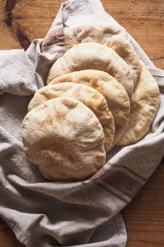 Hacer Pan Pita casero no puede ser más sencillo, increíble pero real. Queda tierno, suave y, lo más importante, hueco sin necesidad de complicarnos. Puedes preparar la masa el día de antes y dejarla levar en nevera toda la noche si quieres, así solo te quedará formar las porciones al día siguiente y en 2 minutos de horno conseguir globos de pan perfectos. El resultado no tiene comparación con ningún pan pita de supermercado, te lo aseguro (y si alguno no se te hincha. queda mejor casero ¡igualmente! El sabor es incomparable al de las versiones industriales). | Receta de Paula's Apron