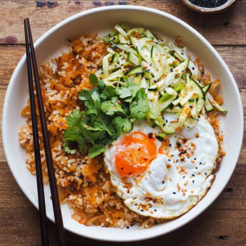 El plato de hoy te puede salvar muchas comidas y cenas si tienes arroz blanco en la nevera del día anterior y un bote de kimchi: Mi Versión de Kimchi Fried Rice (Arroz Frito Estilo Coreano), al que le he añadido una ensalada de calabacín que le va genial para equilibrar sabores y aportar frescura). Puedes tunearlo de mil formas y como cualquier buena receta de arroz frito es fácil y muy versátil (en notas te dejo ideas para adaptarla). | Receta de Paula's Apron