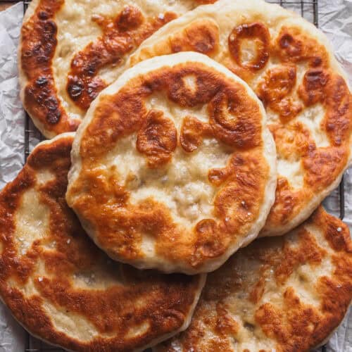 Sin duda, este Pan Plano sin Amasar, Fácil, Extra Tierno y Esponjoso se ha convertido en mi receta de pan plano por defecto de lo increíble que queda. Solo necesitas un puñado de ingredientes que seguro que tienes por la despensa, yogur y levadura, a esto le sumas el reposo para que leve ¡pero no vamos a amasar! Así que 10 minutos máximo de trabajo en total para medir y mezclar, un poco de tiempo para que la levadura haga su magia, hacer porciones y cocinar. Como resultado un pan plano irresistible, perfecto para rellenar y mojar en mil dips y salsas. | Receta de Paula's Apron