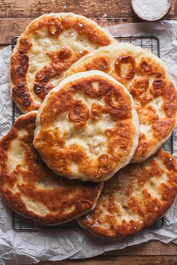 Sin duda, este Pan Plano sin Amasar, Fácil, Extra Tierno y Esponjoso se ha convertido en mi receta de pan plano por defecto de lo increíble que queda. Solo necesitas un puñado de ingredientes que seguro que tienes por la despensa, yogur y levadura, a esto le sumas el reposo para que leve ¡pero no vamos a amasar! Así que 10 minutos máximo de trabajo en total para medir y mezclar, un poco de tiempo para que la levadura haga su magia, hacer porciones y cocinar. Como resultado un pan plano irresistible, perfecto para rellenar y mojar en mil dips y salsas. | Receta de Paula's Apron