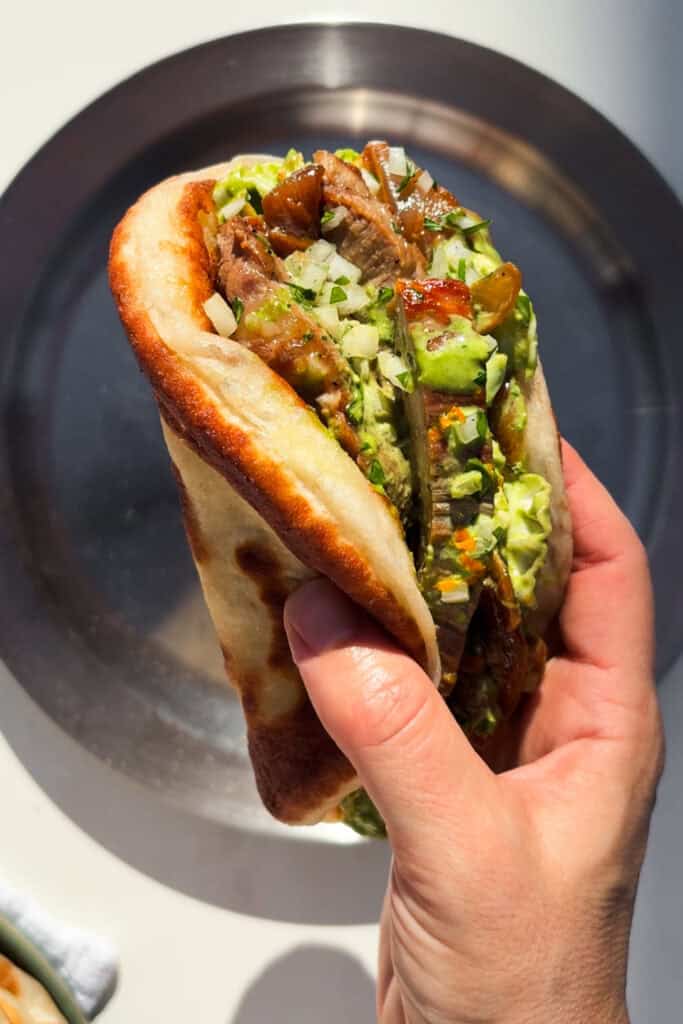 Nueva receta para alegrar tus comidas o cenas: Tacos Fáciles de Secreto Ibérico con Ensalada de Col Green Goddess, Cebolla Caramelizada y Pan Plano. Porque está muy bien hacerse una carne a la plancha y acompañarla de alguna ensalada u otras cosillas, pero todo con pan mejora jeje. Coge los componentes y úsalos juntos como vamos a ver hoy o por separado en otras recetas, haz extra de cada cosa (excepto de carne) y crea mil platos diferentes a partir de este durante el resto de la semana. | Receta de Paula's Apron