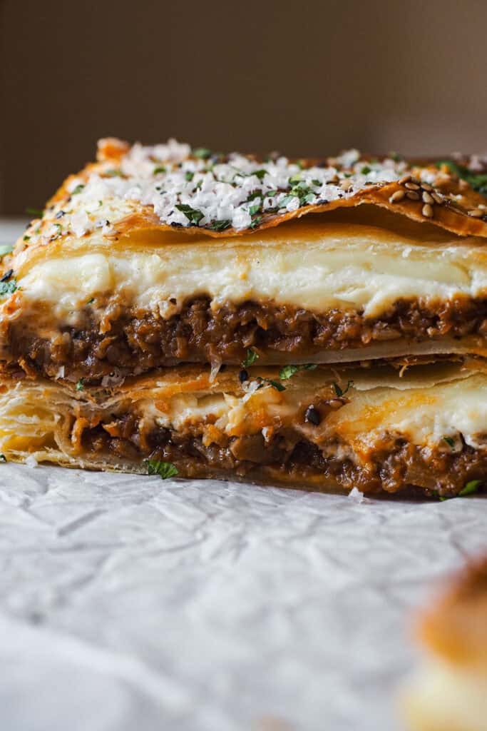 Este pastel de hojaldre relleno de boloñesa de coliflor es como una lasaña envuelta en hojaldre: crujiente por fuera y con un relleno tan sabroso y cremoso que sorprende a cualquiera. Es vegetariano, porque la boloñesa es 100% vegana. Es simplemente una receta reconfortante, diferente y perfectísima para ocasiones especiales como Navidad. | Receta de Paula's Apron